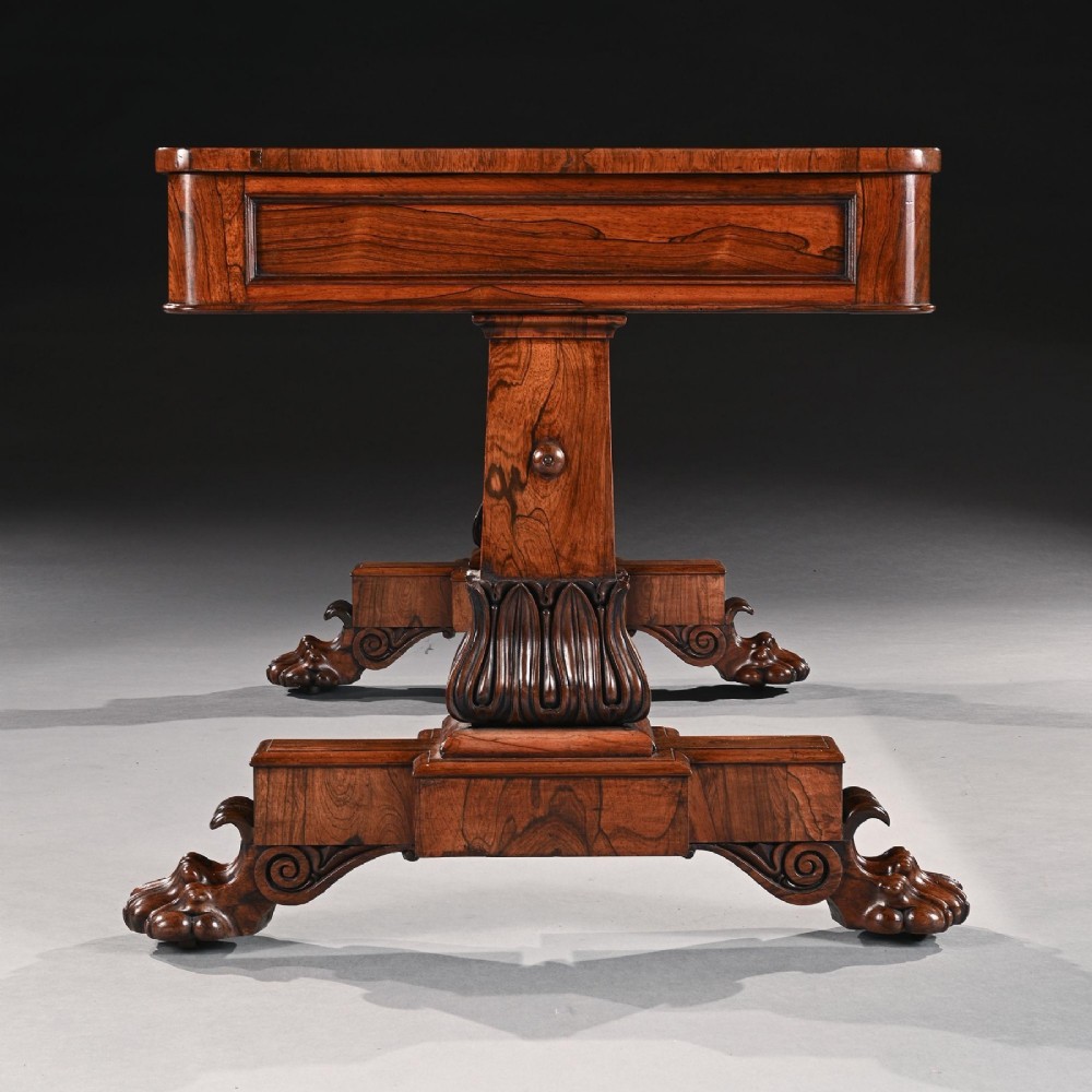 A George IV rosewood library table featuring frieze drawers, a turned stretcher, carved gadrooned supports, and lion paw feet. View V
