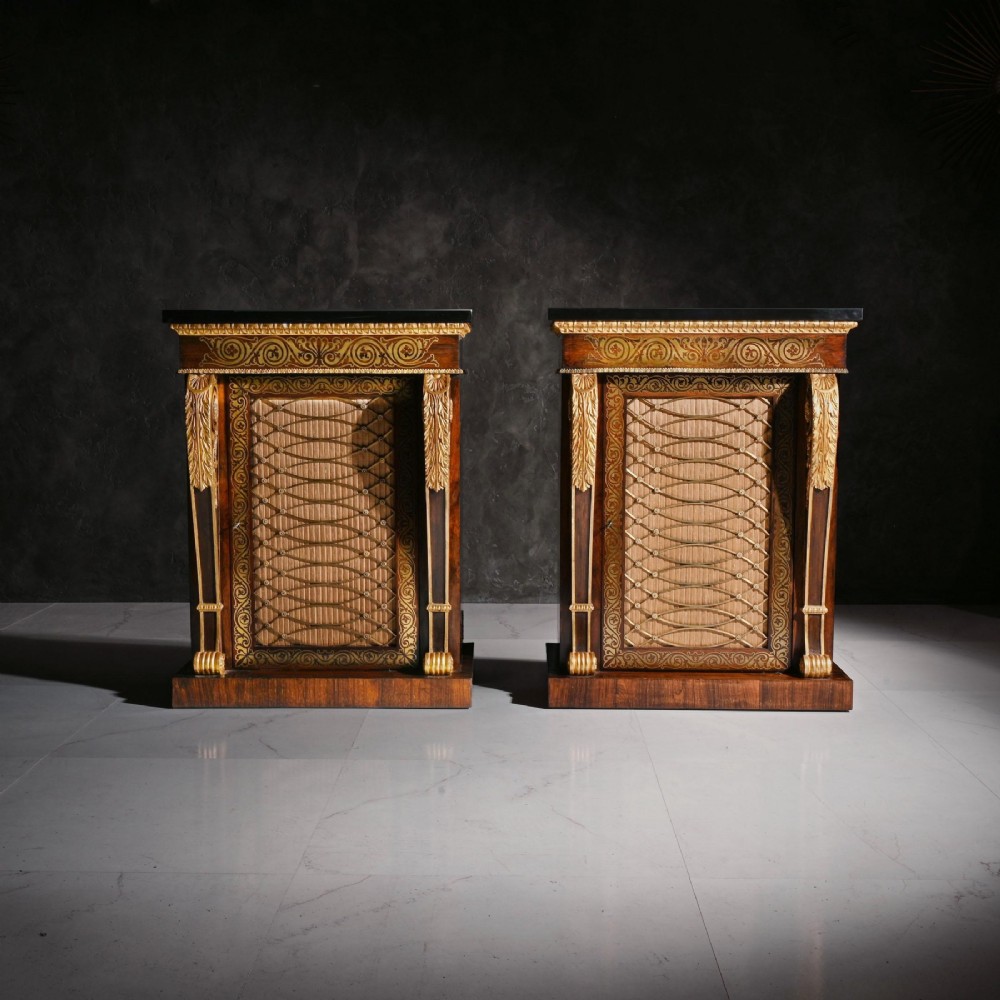 A pair of Regency period dark wood side cabinets featuring brass marquetry inlay, gilded term supports, and brass mesh doors lined with fabric. View II