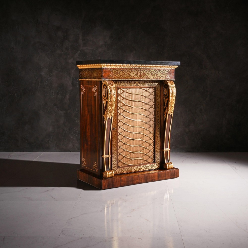 A pair of Regency period dark wood side cabinets featuring brass marquetry inlay, gilded term supports, and brass mesh doors lined with fabric. View IV