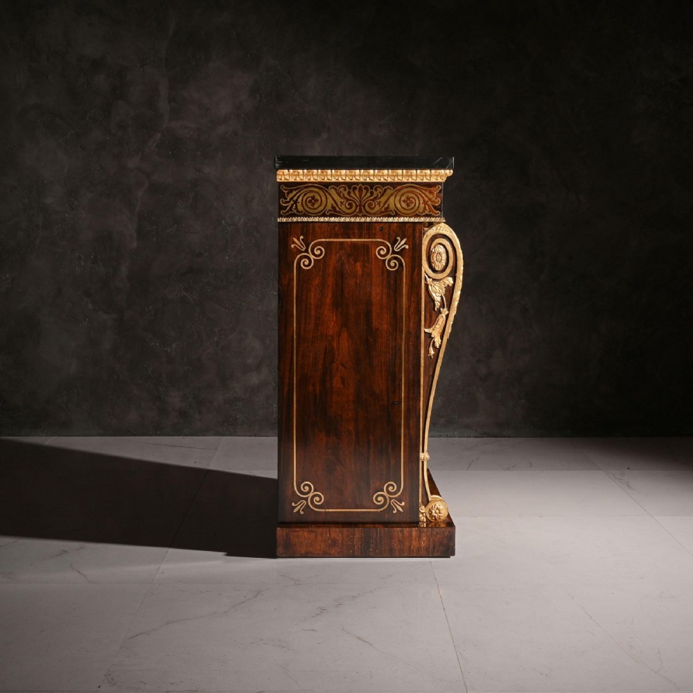 A pair of Regency period dark wood side cabinets featuring brass marquetry inlay, gilded term supports, and brass mesh doors lined with fabric. View VI