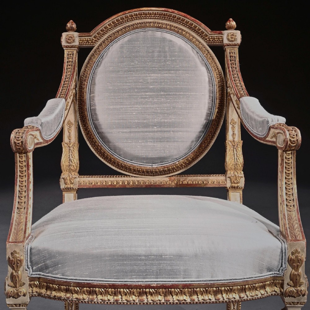 A pair of 19th-century Italian Neoclassical armchairs featuring oval backrests, cream and parcel-gilt carved frames, fluted legs, and grey silk upholstery. View XII