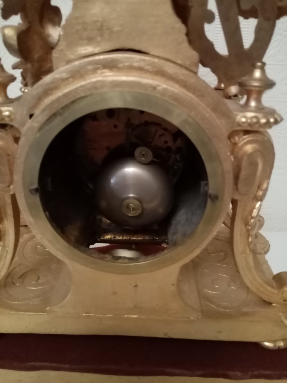 An ornate gold gilt bronze mantel clock topped with a seated cherub figure writing on a scroll above an enamelled dial with Roman numerals. View VIII