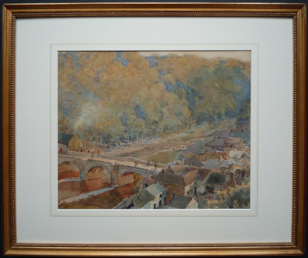 A watercolour painting depicting a stone arch bridge spanning a river alongside town houses and a wooded hillside, signed Fred Stead. View II
