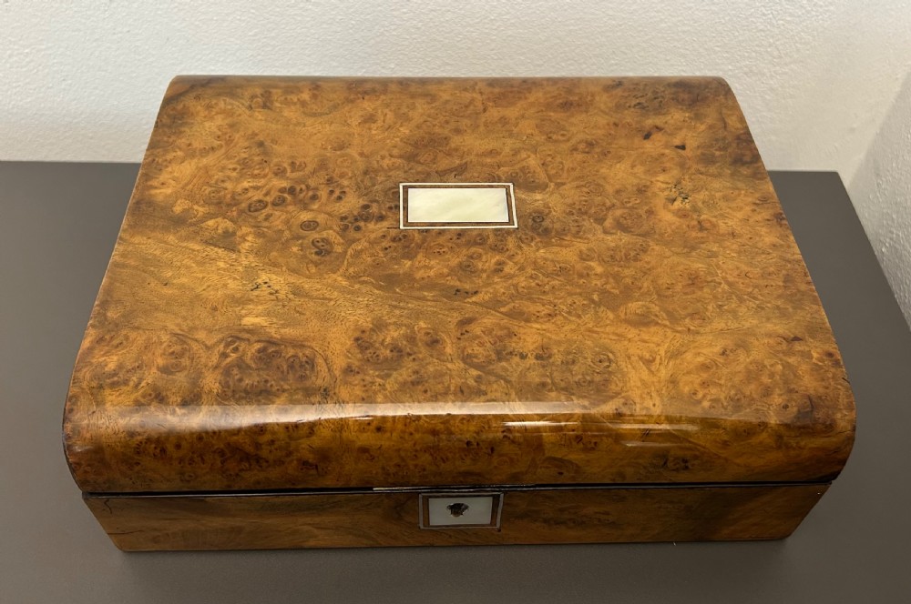 A rectangular Victorian burr walnut box featuring rounded edges, a mother-of-pearl central cartouche inlay, and a matching keyhole escutcheon. View VIII