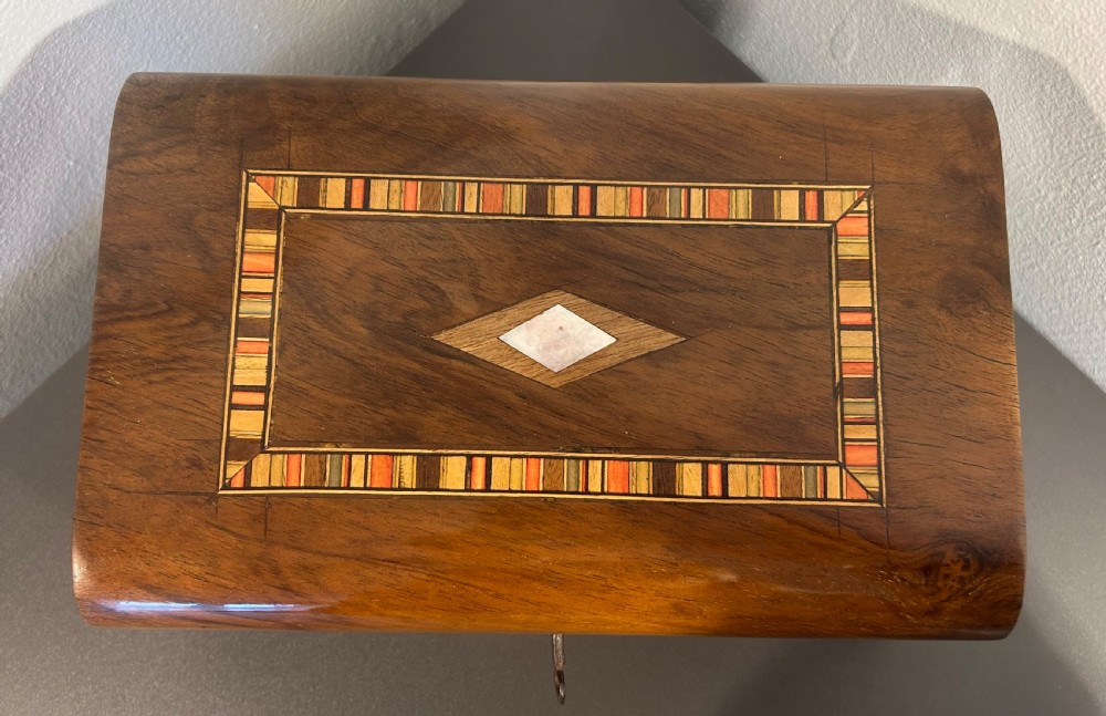 Victorian burr walnut wooden box with a geometric mosaic inlay border, central mother of pearl lozenge motif, and key in the front lock. View VIII