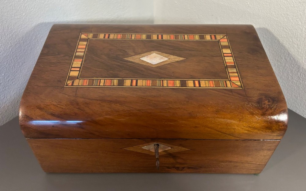 Victorian burr walnut wooden box with a geometric mosaic inlay border, central mother of pearl lozenge motif, and key in the front lock. View IX