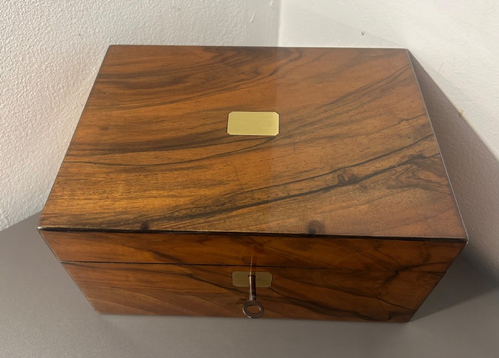A rectangular warm brown figured walnut box featuring a brass cartouche on the lid and a brass escutcheon with a key. View II