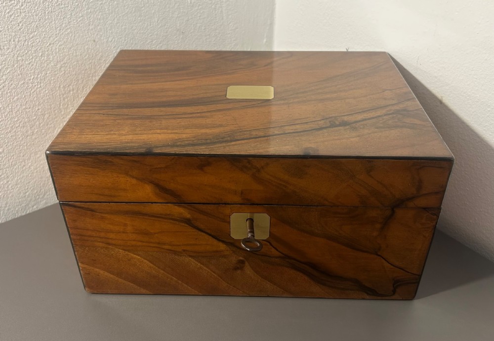 A rectangular warm brown figured walnut box featuring a brass cartouche on the lid and a brass escutcheon with a key. View III