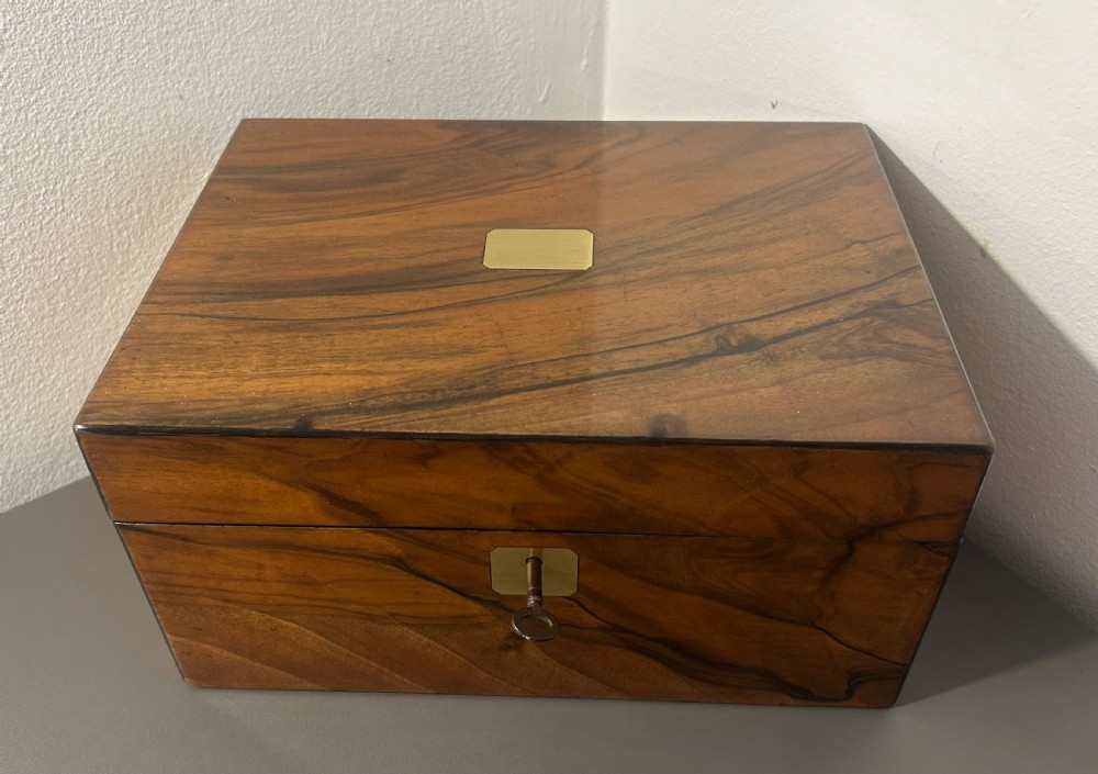 A rectangular warm brown figured walnut box featuring a brass cartouche on the lid and a brass escutcheon with a key. View IV