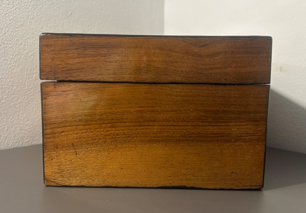 A rectangular warm brown figured walnut box featuring a brass cartouche on the lid and a brass escutcheon with a key. View VIII