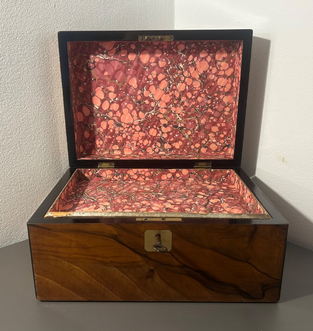 A rectangular warm brown figured walnut box featuring a brass cartouche on the lid and a brass escutcheon with a key. View IX