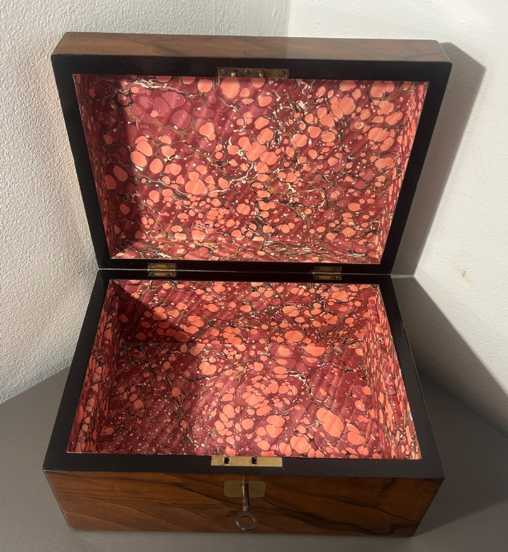 A rectangular warm brown figured walnut box featuring a brass cartouche on the lid and a brass escutcheon with a key. View XI