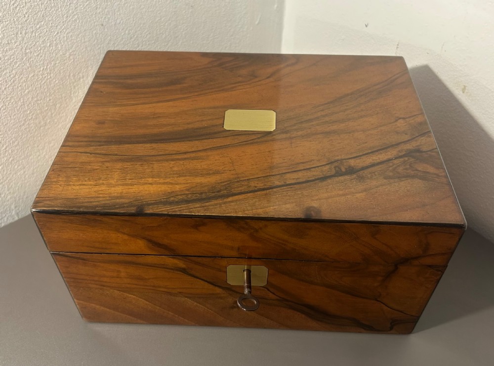 A rectangular warm brown figured walnut box featuring a brass cartouche on the lid and a brass escutcheon with a key. View XII