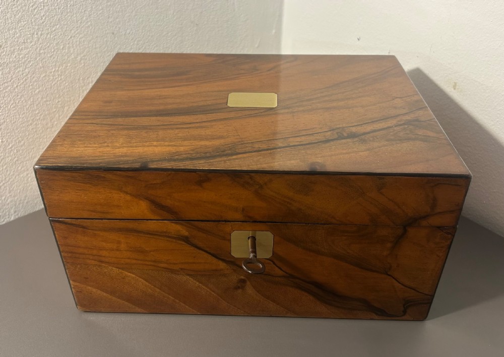 A rectangular warm brown figured walnut box featuring a brass cartouche on the lid and a brass escutcheon with a key. View XIII
