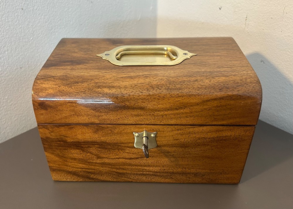 A Victorian warm brown walnut jewellery box featuring a domed lid, inset brass handle, and a brass key inserted into the front escutcheon. View II