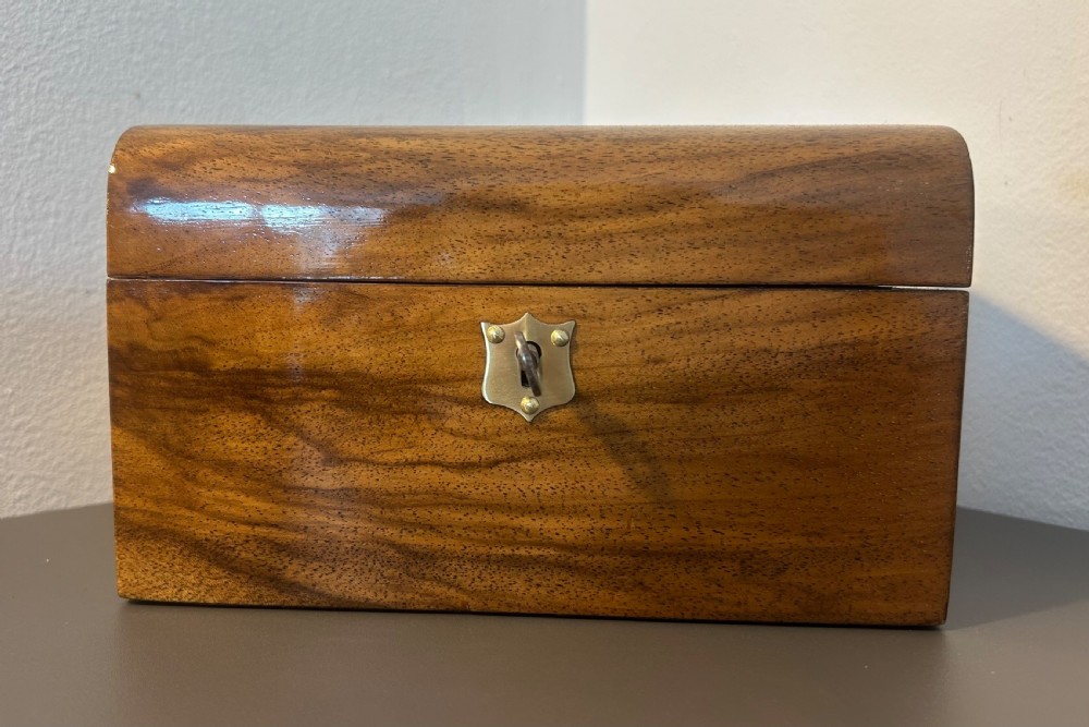 A Victorian warm brown walnut jewellery box featuring a domed lid, inset brass handle, and a brass key inserted into the front escutcheon. View III
