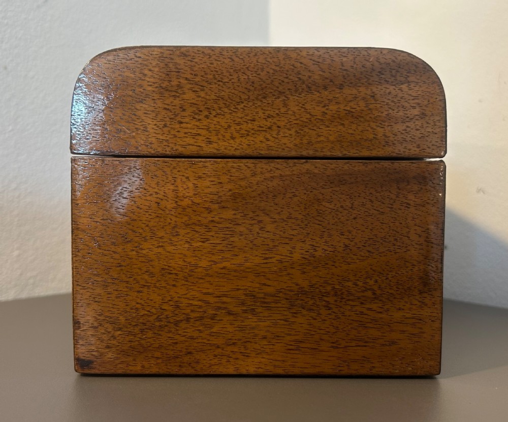 A Victorian warm brown walnut jewellery box featuring a domed lid, inset brass handle, and a brass key inserted into the front escutcheon. View V