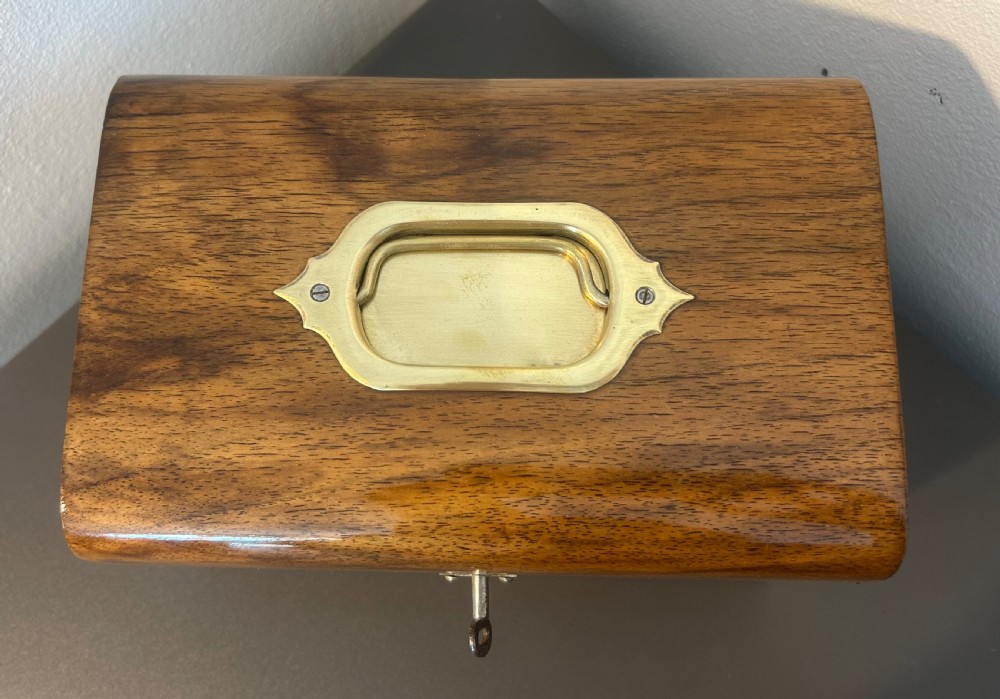 A Victorian warm brown walnut jewellery box featuring a domed lid, inset brass handle, and a brass key inserted into the front escutcheon. View IX