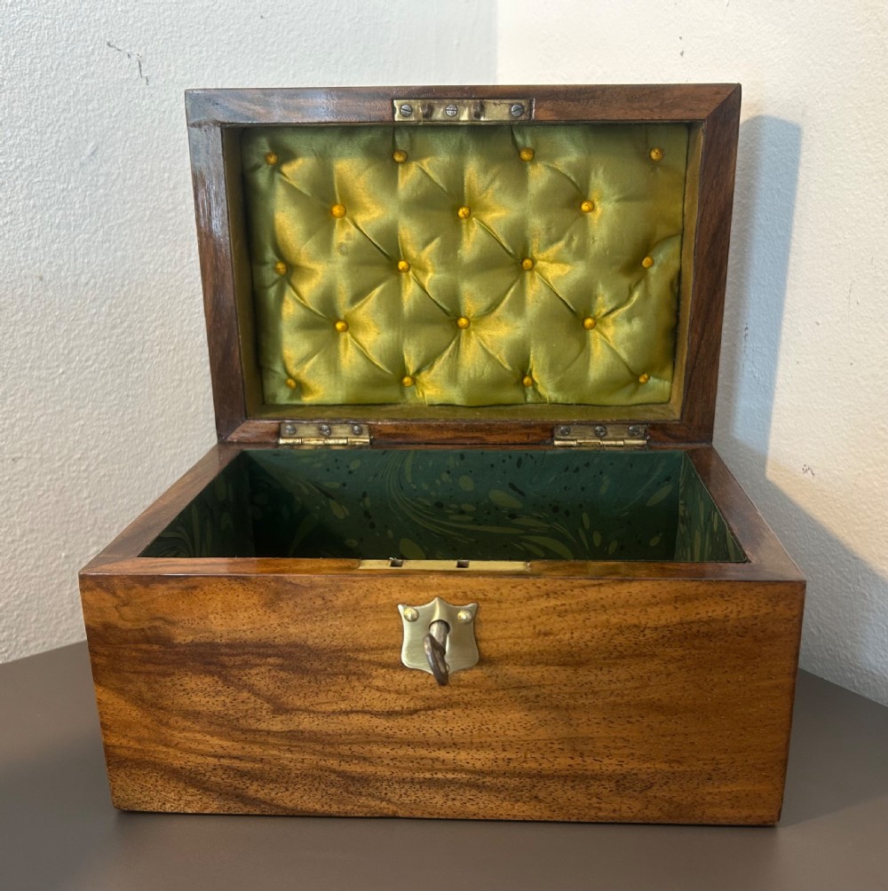 A Victorian warm brown walnut jewellery box featuring a domed lid, inset brass handle, and a brass key inserted into the front escutcheon. View XII