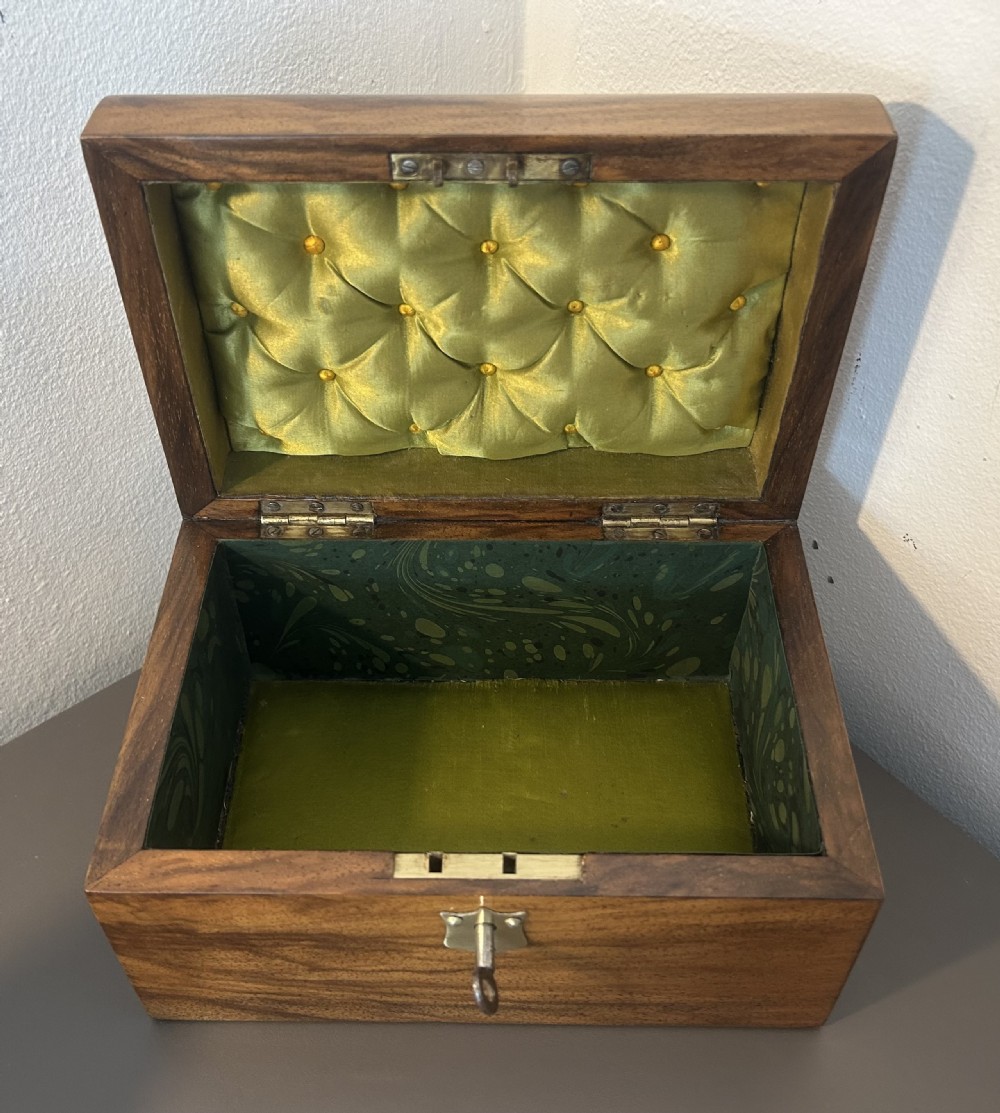 A Victorian warm brown walnut jewellery box featuring a domed lid, inset brass handle, and a brass key inserted into the front escutcheon. View XIII
