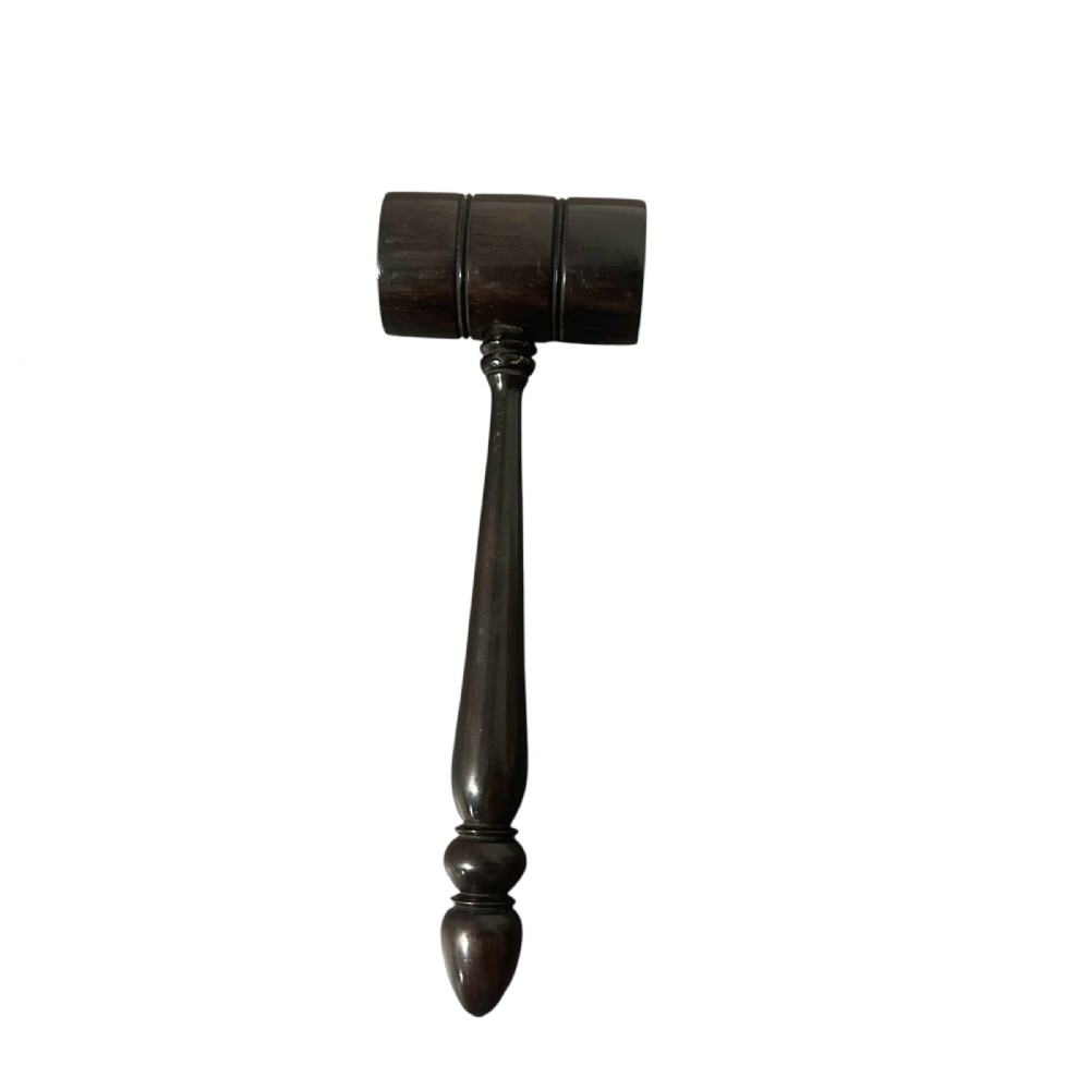 A turned dark ebony wood gavel featuring a cylindrical head with incised ring details and a lathe-turned handle ending in a rounded finial.