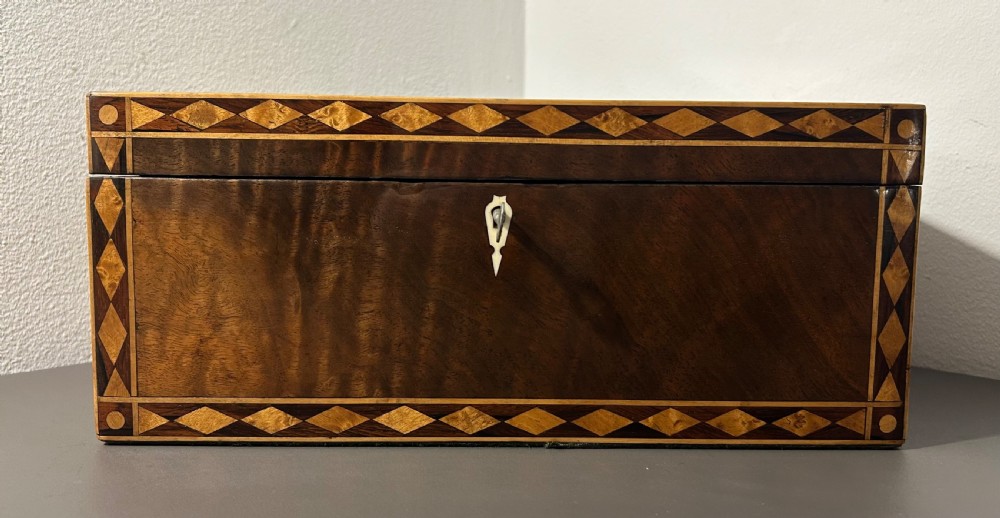 A rectangular Victorian specimen wood box featuring geometric parquetry inlay, a central heart motif on the lid, and a keyhole on the front. View VI