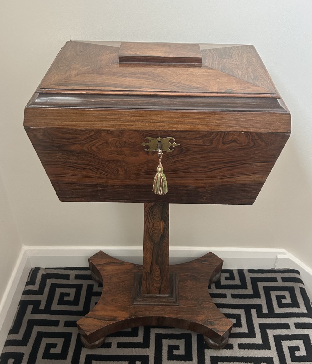 A Regency rosewood teapoy featuring a sarcophagus-shaped caddy top, brass escutcheon with key and tassel, set upon a central column and a four-pointed concave base. View III