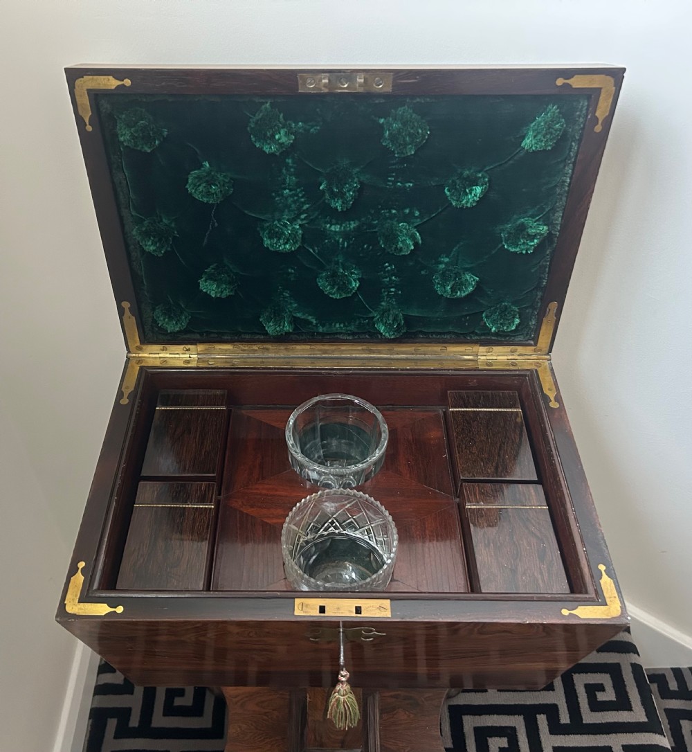A Regency rosewood teapoy featuring a sarcophagus-shaped caddy top, brass escutcheon with key and tassel, set upon a central column and a four-pointed concave base. View XII