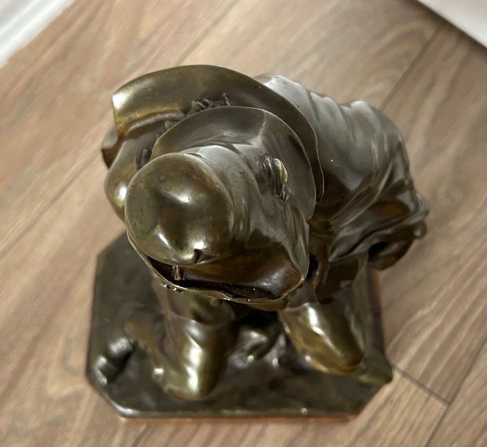 A patinated dark bronze sculpture depicting a seated male musician with a hurdy-gurdy instrument and a small dog at his feet on a wooden plinth. View VII