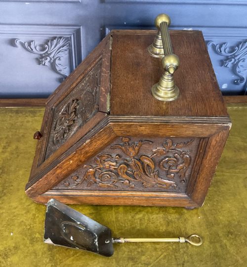 fig 1. A Victorian carved oak coal scuttle featuring a brass top handle and a sloped front panel relief-carved with a mythical sea creature.