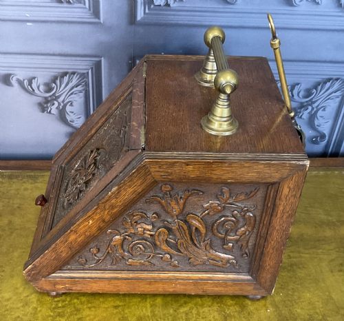 fig 2. A Victorian carved oak coal scuttle featuring a brass top handle and a sloped front panel relief-carved with a mythical sea creature.