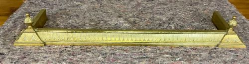 fig 1. An antique Victorian brass fireplace fender featuring embossed leaf patterning along the curb and turned finials on each corner block.