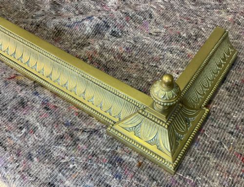 fig 2. An antique Victorian brass fireplace fender featuring embossed leaf patterning along the curb and turned finials on each corner block.