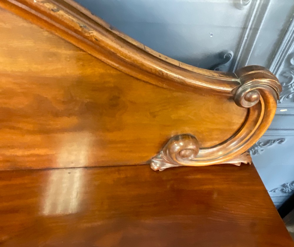 A Victorian mahogany pedestal sideboard featuring a carved arched backboard, flame mahogany veneer panels, and twin pedestal cupboards. View IX