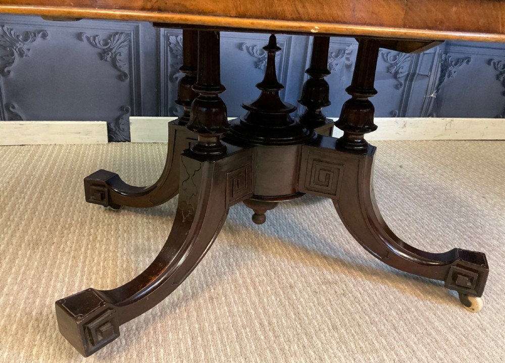 An oval Victorian low coffee table featuring a bookmatched burr walnut veneer top supported by dark curved legs on small castors. View IV