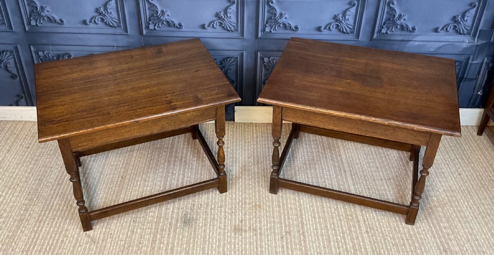 A matching pair of dark oak rectangular coffee tables featuring turned legs and low perimeter stretchers.