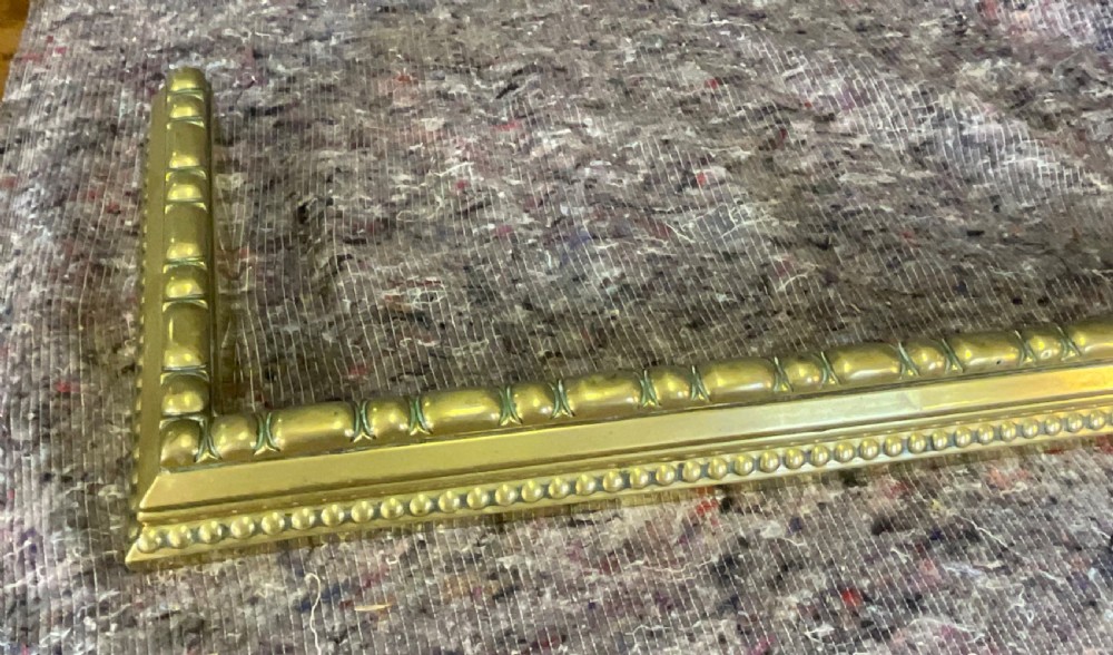 A three-sided Victorian polished brass fireplace fender featuring beaded moulding details along its frame. View III