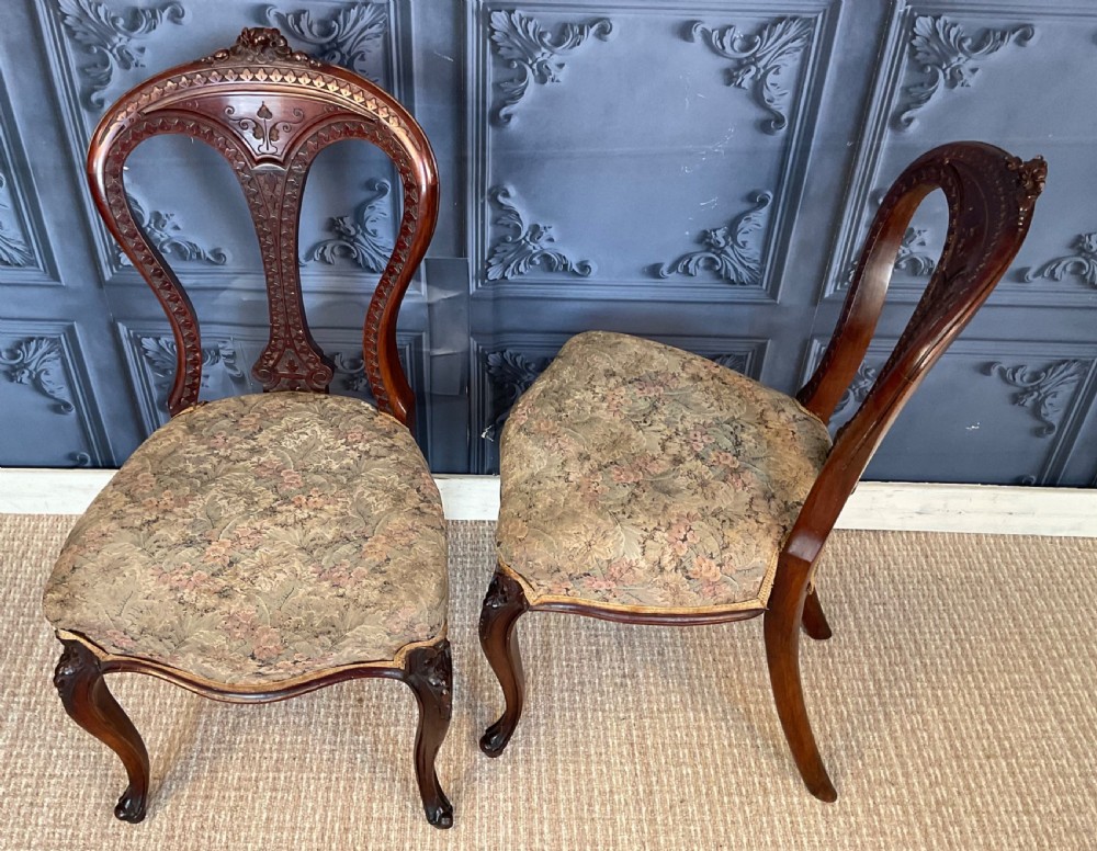 A pair of Victorian carved dark wood side chairs featuring open-work balloon backs, patterned tapestry upholstered seats, and cabriole legs. View VII