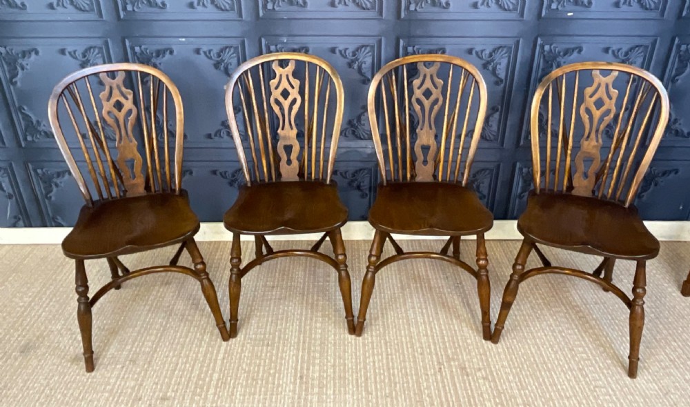 A set of four warm brown wooden Windsor style dining chairs with hoop backs, pierced central splats, and turned legs. View II