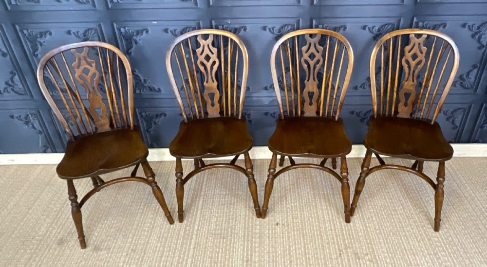A set of four warm brown wooden Windsor style dining chairs with hoop backs, pierced central splats, and turned legs. View III