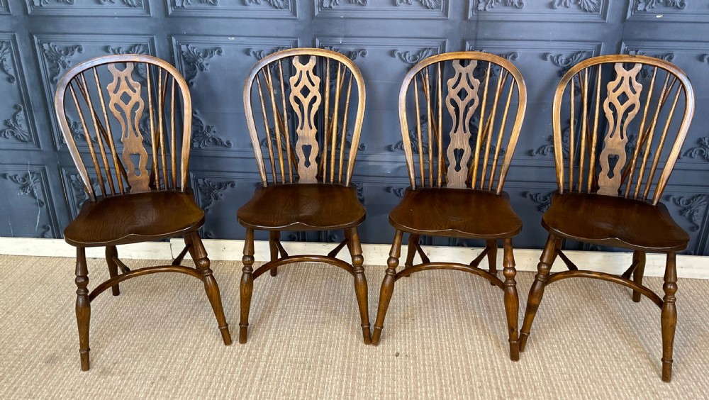 A set of four warm brown wooden Windsor style dining chairs with hoop backs, pierced central splats, and turned legs. View IV