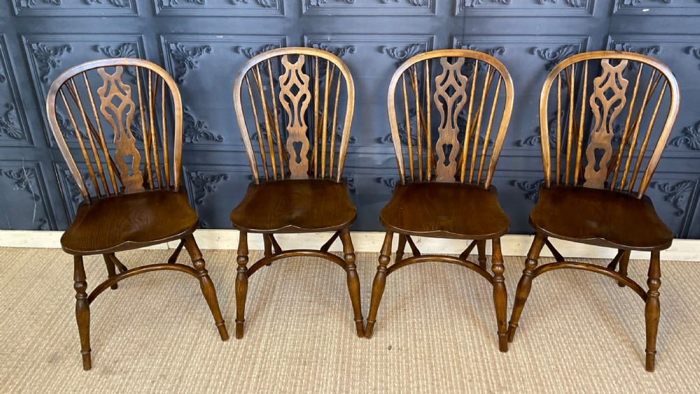 A set of four warm brown wooden Windsor style dining chairs with hoop backs, pierced central splats, and turned legs. View V
