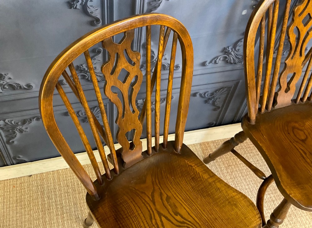 A set of four warm brown wooden Windsor style dining chairs with hoop backs, pierced central splats, and turned legs. View VI