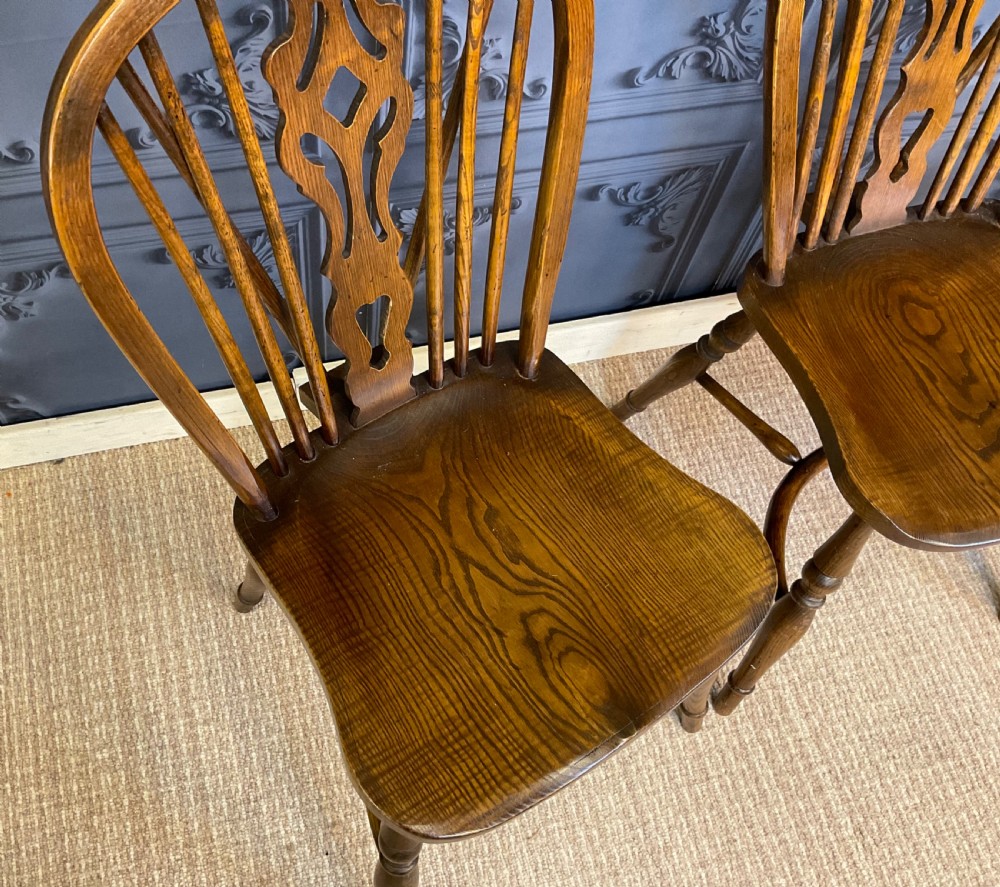 A set of four warm brown wooden Windsor style dining chairs with hoop backs, pierced central splats, and turned legs. View VII
