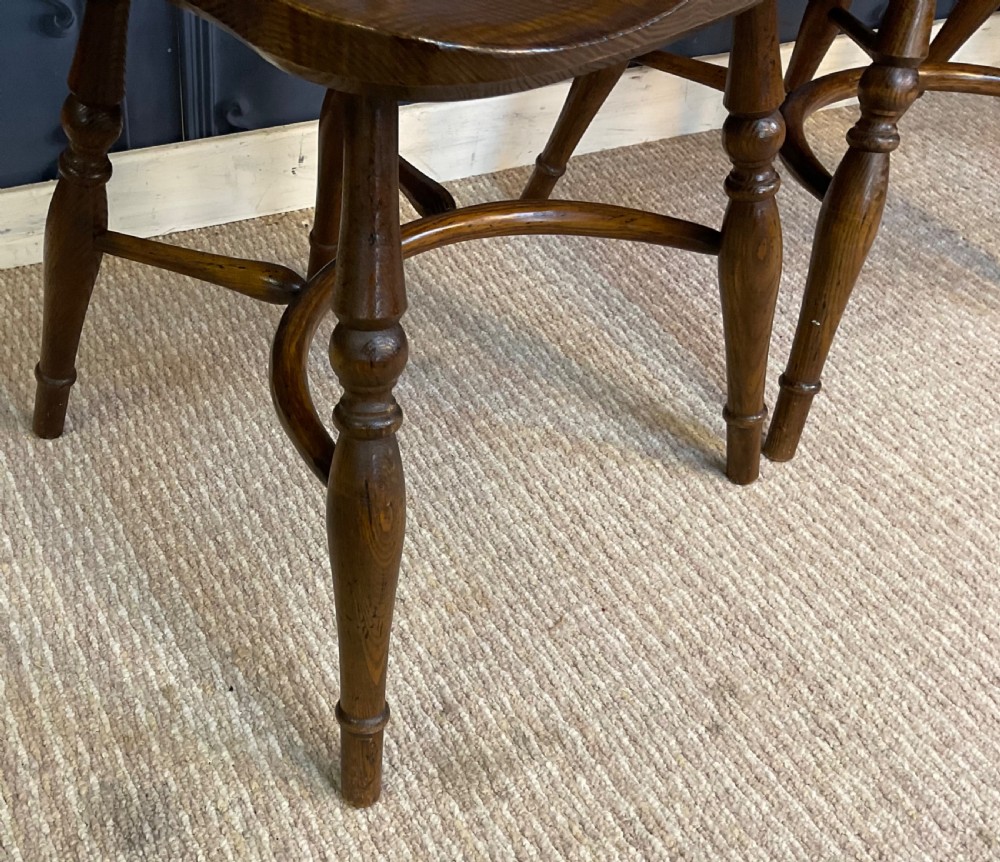 A set of four warm brown wooden Windsor style dining chairs with hoop backs, pierced central splats, and turned legs. View IX