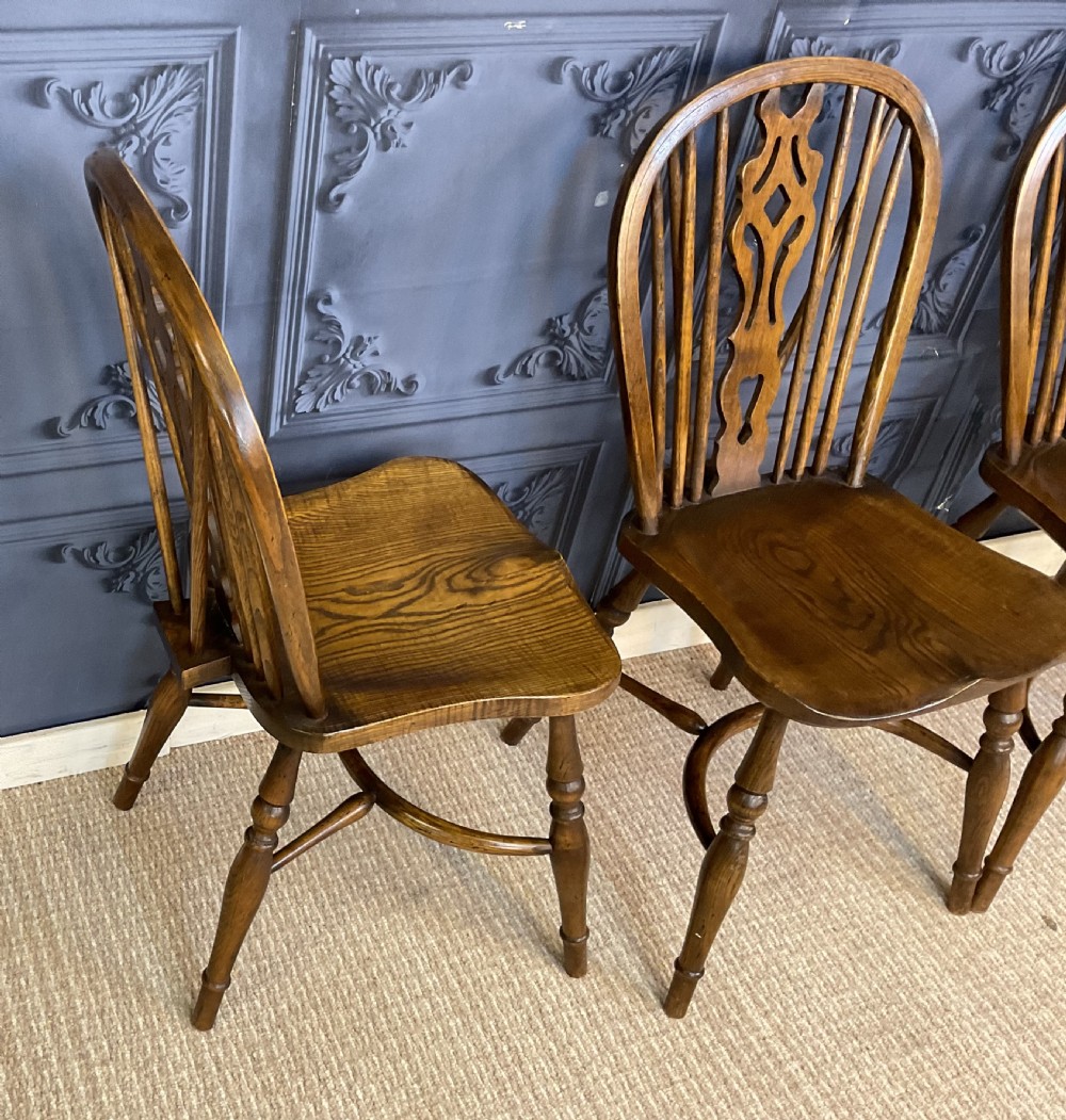 A set of four warm brown wooden Windsor style dining chairs with hoop backs, pierced central splats, and turned legs. View X