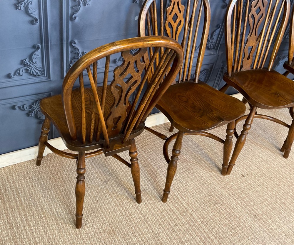 A set of four warm brown wooden Windsor style dining chairs with hoop backs, pierced central splats, and turned legs. View XI