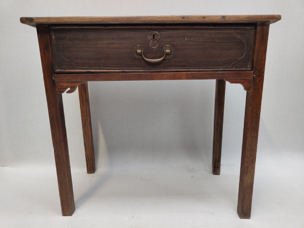 A rustic brown timber side table featuring a single central drawer with a brass drop handle and straight square legs.