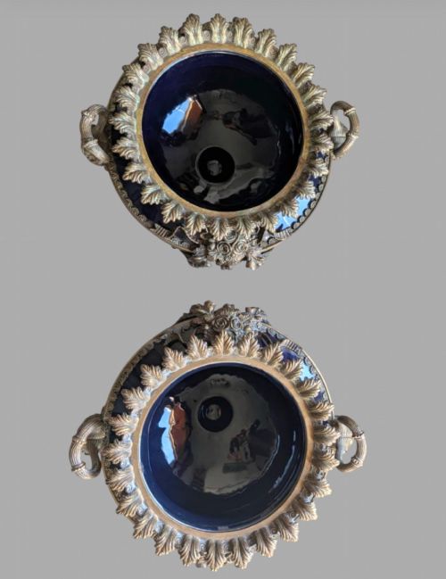 fig 1. A pair of deep cobalt blue glazed ceramic urn-shaped jardinieres adorned with ornate gilt bronze mounts, floral swags, and decorative handles, set on footed bases.