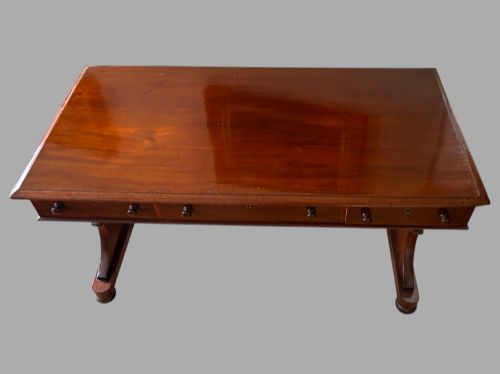 fig 1. A rectangular mahogany library table featuring three frieze drawers with round timber handles and a lower turned stretcher resting on shaped trestle feet.